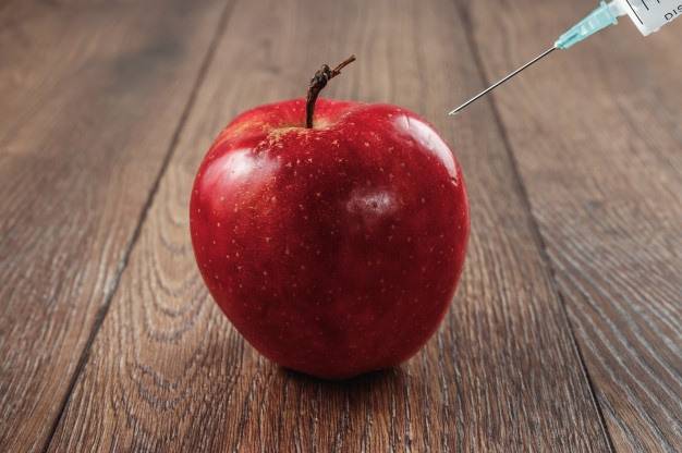 red apple injecting needle syringe chemical pesticides wooden background 99433 841 ac906c43d26b8ce742dfa47f9358213b